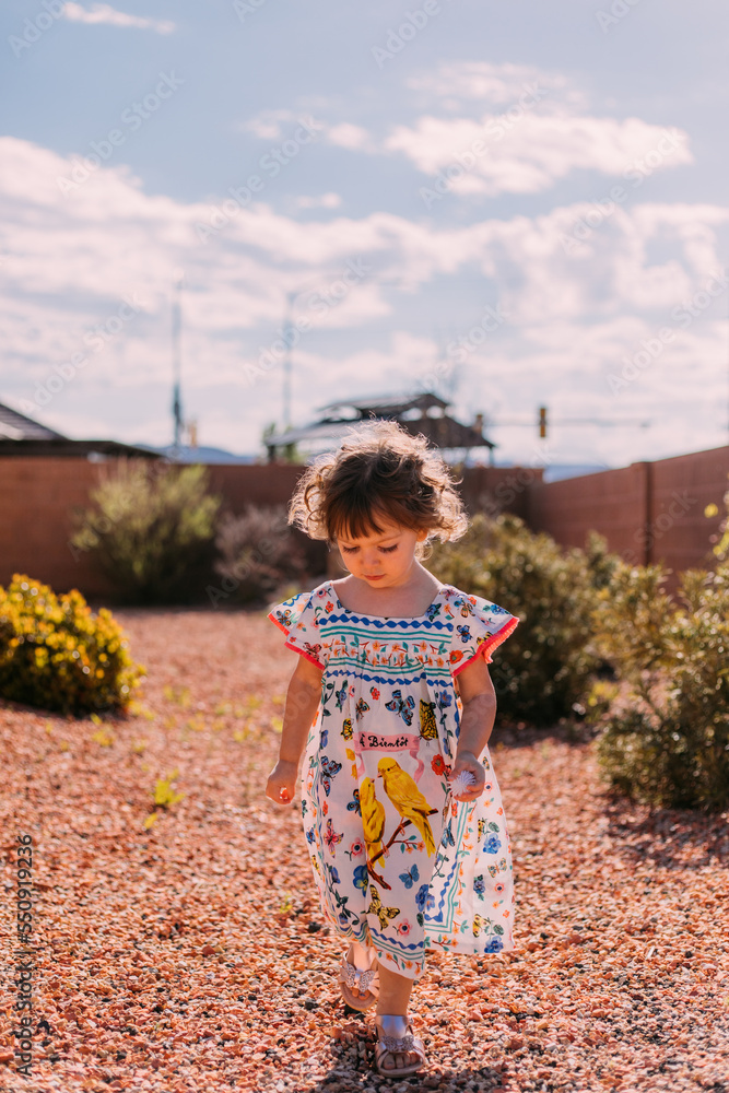 Little girl with curly hair walking outside in a colorful dress Little girl with curly hair walking outside in a colorful dress