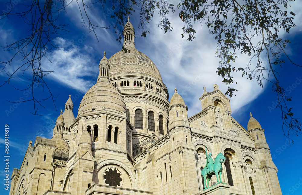 Beautiful closeup view on isolated dome of Sacre Coeur church, autumn tree branches, clear blue spectacular sky, fluffy cloud - Paris, France