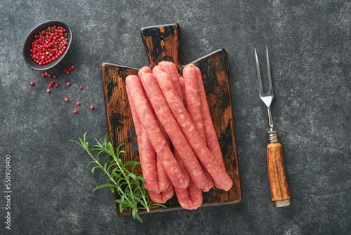 Meat beef sausages. Raw barbecue sausages with spices, vegetables and ingredients for cooking on black background. Top view. Copy space. Oktoberfest menu concept.