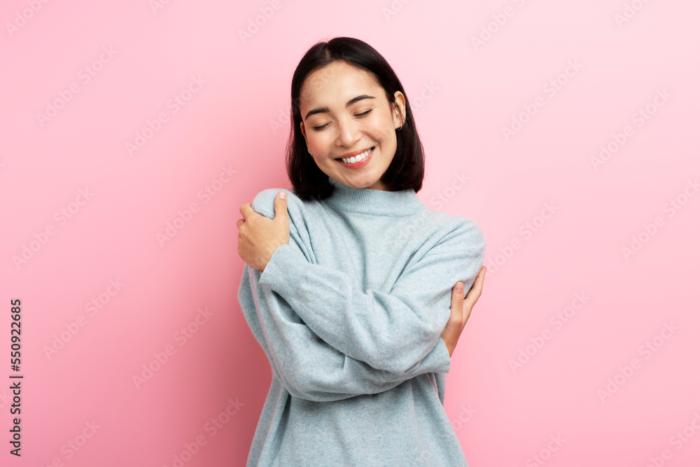 Portrait of self-satisfied egoistic woman embracing herself and smiling with pleasure - obrazy, fototapety, plakaty 