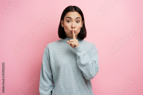 Portrait of serious woman showing silence gesture with finger on her mouth