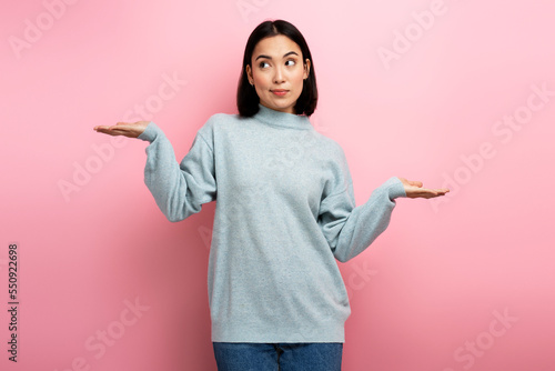 Portrait of uncertain confused girl in sweater expressing doubts and bewilderment