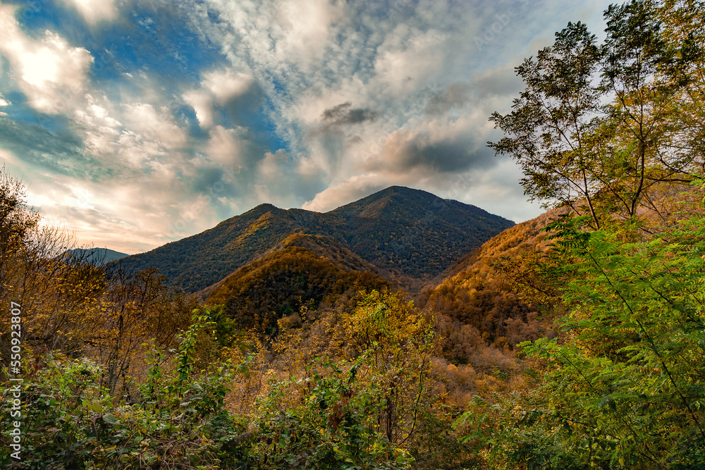Fototapeta premium High mountains under a blue cloudy sky. Autumn in the foothills of the Caucasus.. Beautiful mountain landscape in autumn. Autumn view of the mountains. Nature in the autumn forest.