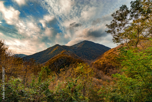High mountains under a blue cloudy sky. Autumn in the foothills of the Caucasus.. Beautiful mountain landscape in autumn. Autumn view of the mountains. Nature in the autumn forest.