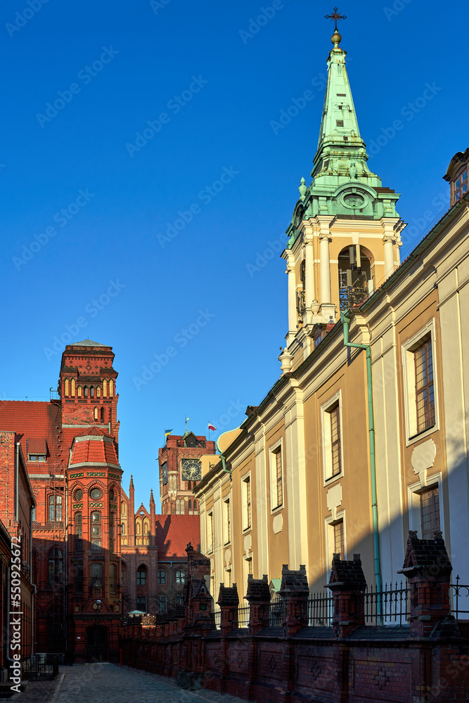 The belfry of a church and facades of historic tenement houses in Torun