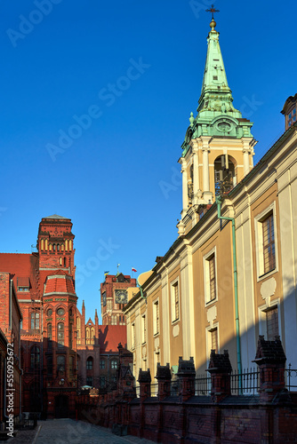 The belfry of a church and facades of historic tenement houses in Torun