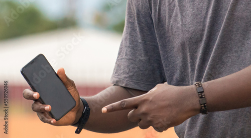 Hand of young black african man holding white blank screen smartphone