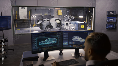 An engineer in a crash test lab uses a car crash test system to simulate a traffic accident, to obtain the safety parameters of an eco-friendly cutting edge electric vehicle being developed.