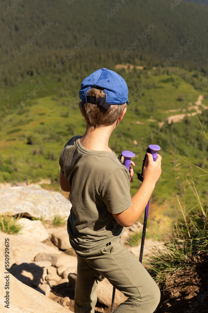 a child descends from the mountain with poles for Nordic walking. A young climber who conquered Hoverla. a child descends from the mountain with poles for Nordic walking. A young climber who conquered Hoverla.