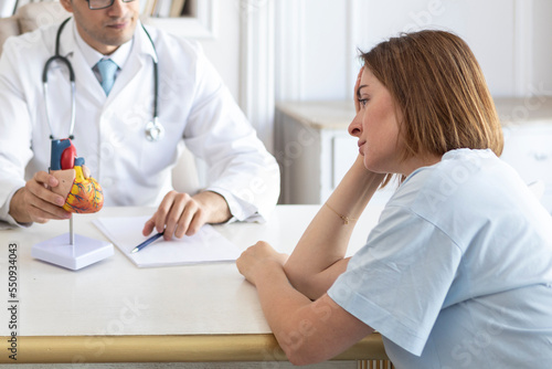 Portrait of young upset female patient and doctor cardiologist working in office of modern clinic