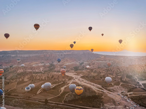 Hot air balloon flying over rocky landscapes in Cappadocia with beautiful sky on background