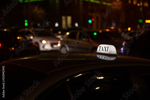 Taxi sign on top of a car, glowing night urban