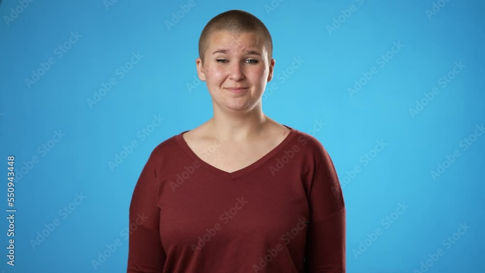 Portrait of gender fluid non binary young woman 20s years old posing isolated on blue background studio. Cover mouth with hands on face say wow omg no way Portrait of gender fluid non binary young woman 20s years old posing isolated on blue background studio. Cover mouth with hands on face say wow omg no way