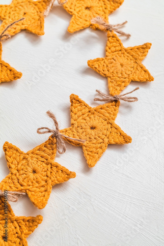 Christmas yellow crochet garland on a white background. Handmade crochet star shaped garland.