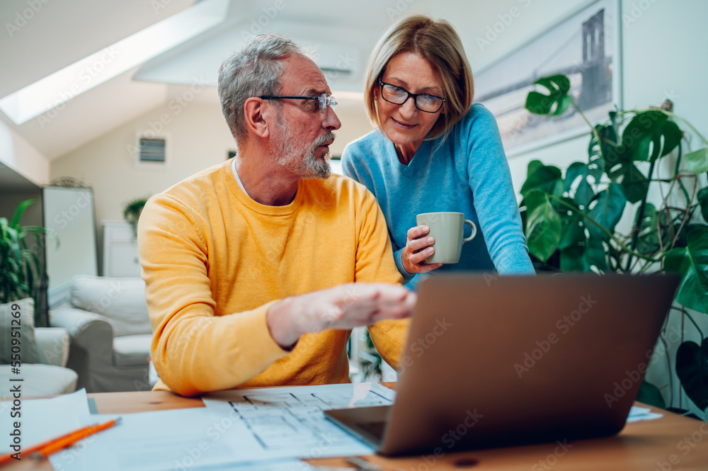 Senior middle aged happy couple using laptop together at home Senior middle aged happy couple using laptop together at home
