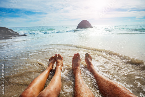 Photo of adult and child feet in sea waves at summer vacation photo