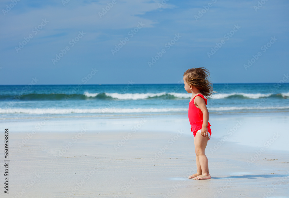 Beautiful girl stand on ocean sand beach in swimsuit, profile Beautiful girl stand on ocean sand beach in swimsuit, profile