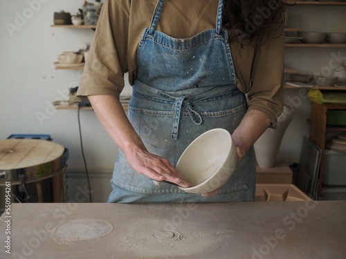 Fotografie Unrecognizable woman ceramist peeling a clay plate holding sponge