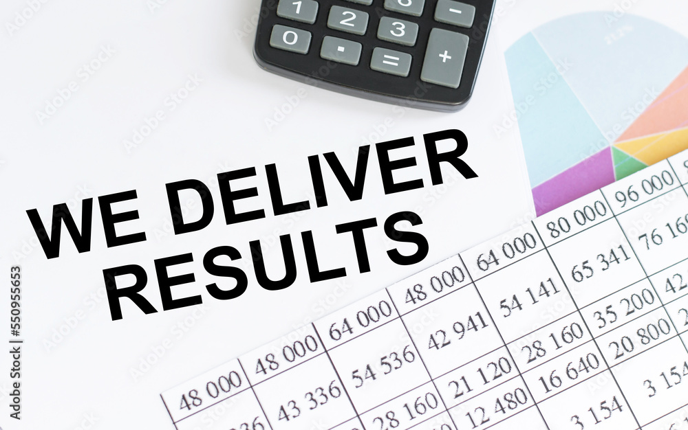 WE DELIVER RESULTS text on notepad on a table with documents with a calculator on the table WE DELIVER RESULTS text on notepad on a table with documents with a calculator on the table