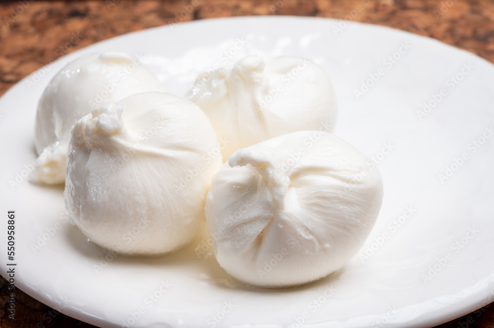 Eating of fresh handmade soft Italian cheese from Puglia, white balls of burrata or burratina cheese made from mozzarella and cream filling Eating of fresh handmade soft Italian cheese from Puglia, white balls of burrata or burratina cheese made from mozzarella and cream filling