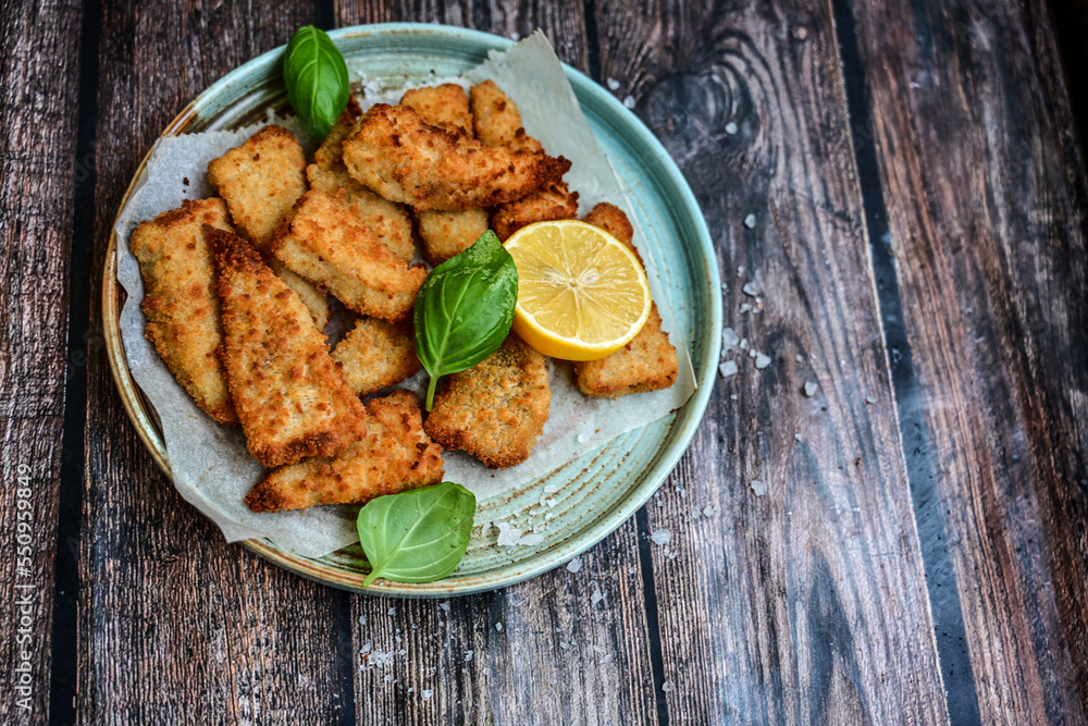 Allasca Pollock Fish Bites in a crispy Tempura Batter.Fish and chips .Close up of crispy breaded deep fried fish fingers with breadcrumbs s erved with remoulade sauce and lemon Allasca Pollock Fish Bites in a crispy Tempura Batter.Fish and chips .Close up of crispy breaded deep fried fish fingers with breadcrumbs s erved with remoulade sauce and lemon