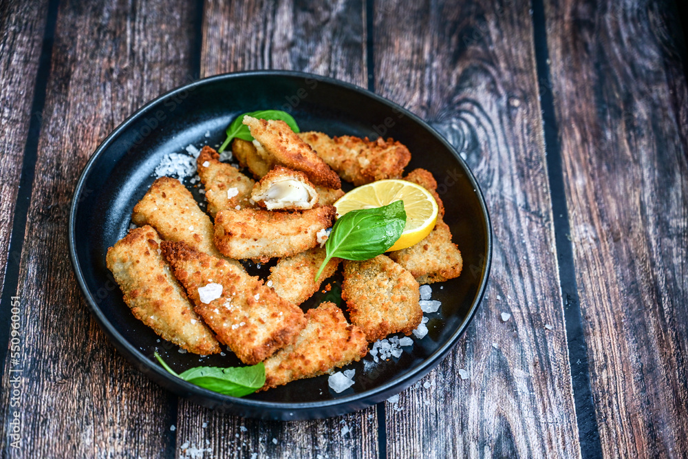 Fototapeta premium Allasca Pollock Fish Bites in a crispy Tempura Batter.Fish and chips .Close up of crispy breaded deep fried fish fingers with breadcrumbs s erved with remoulade sauce and lemon