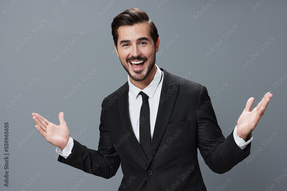Business man has his hands up and is smiling with his teeth open in a business suit on a gray background portrait Business man has his hands up and is smiling with his teeth open in a business suit on a gray background portrait