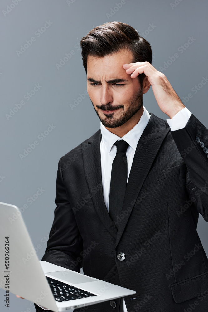 Man business looks into laptop and works thoughtfully online via internet in business suit video call business talks on gray background copy place Man business looks into laptop and works thoughtfully online via internet in business suit video call business talks on gray background copy place