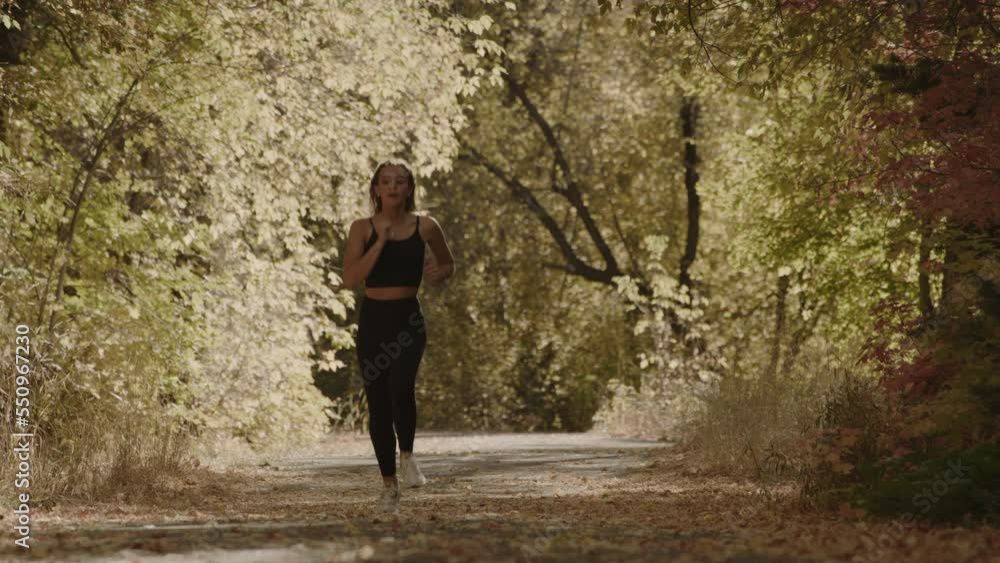 Slow motion of approaching girl running on park path in autumn / American Fork Canyon, Utah, United States Slow motion of approaching girl running on park path in autumn / American Fork Canyon, Utah, United States