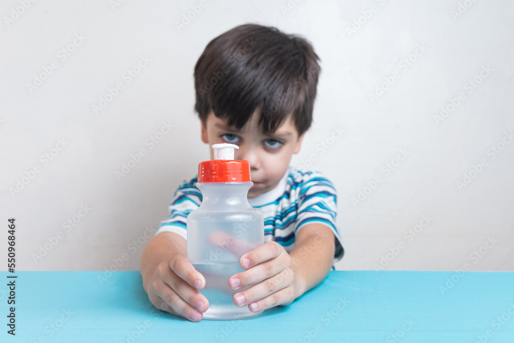Cute, adorable boy in studio drinking water from bottle Cute, adorable boy in studio drinking water from bottle