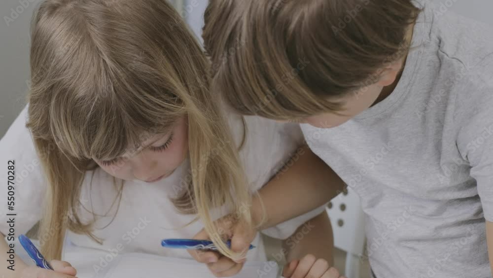 Brother helps his younger sister to make her homework. Brother helps his younger sister to make her homework.