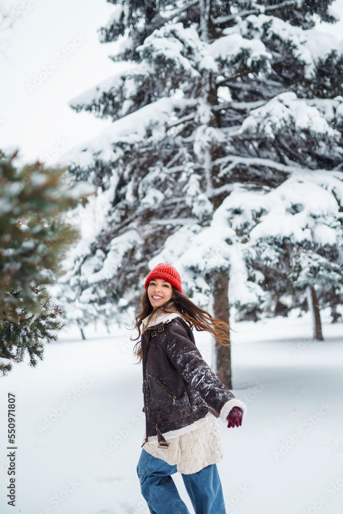 Young woman laughs and throws snow in a winter snowy park. Holidays, rest, travel concept.