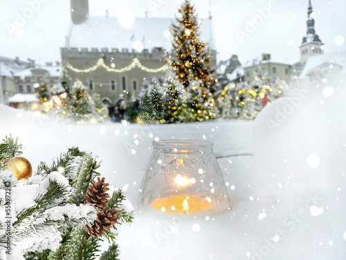 Christmas city , green tree marketplace, candle light in snow , blurred bokeh light illumination, town hall square in Tallinn old town, blowing snoflackes, people walk and celebrate festive winter hol