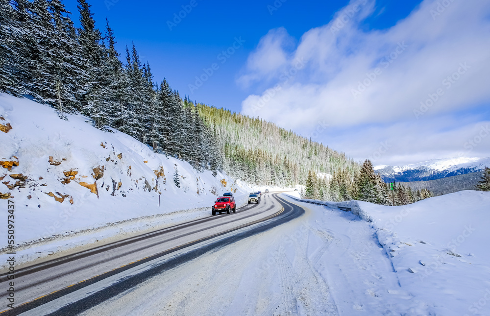 View of mountain highway in Colorado, USA, in winter with driving cars in foreground and sky in background View of mountain highway in Colorado, USA, in winter with driving cars in foreground and sky in background