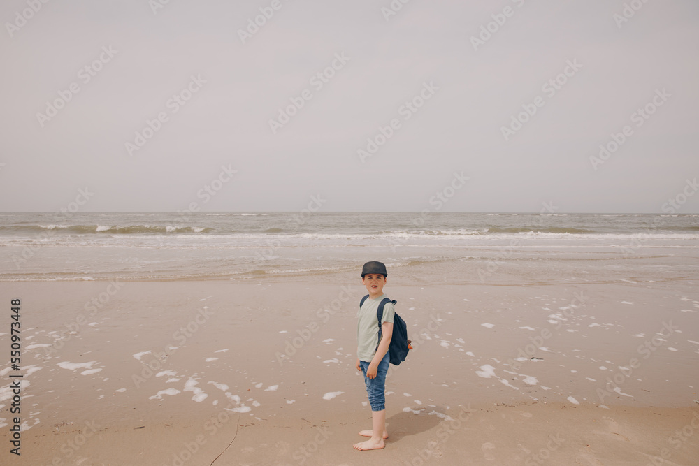Child with a backpack at the Wadden Sea. Vacation in Germany, on the beach on a North Sea island. North Sea and Watt hike