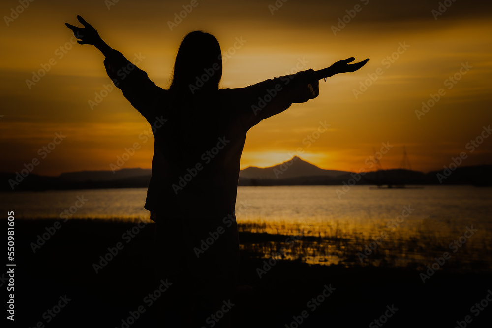 Silhouette back views of a free woman enjoying the freedom and feeling happy at sunrice. Serene relaxing woman in pure happiness nature lake view.