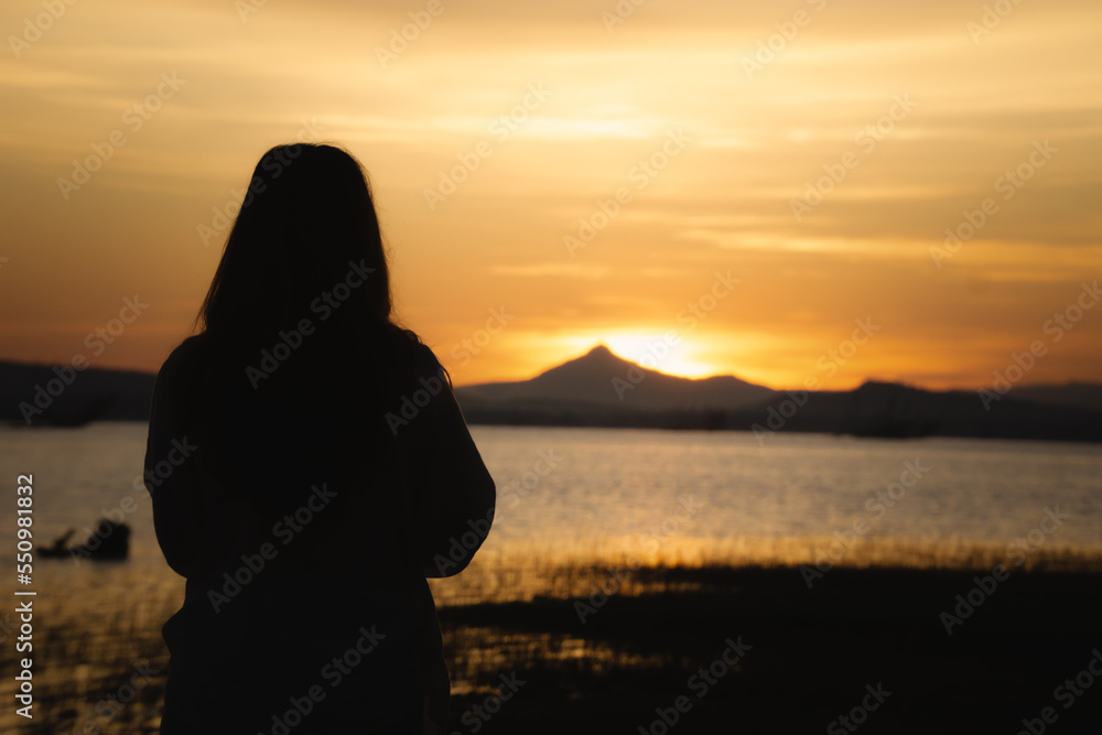 Silhouette back views of a free woman enjoying the freedom and feeling happy at sunrice. Serene relaxing woman in pure happiness nature lake view.