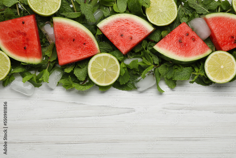 Tasty sliced watermelon, limes, mint and ice on white wooden table, flat lay. Space for text Tasty sliced watermelon, limes, mint and ice on white wooden table, flat lay. Space for text