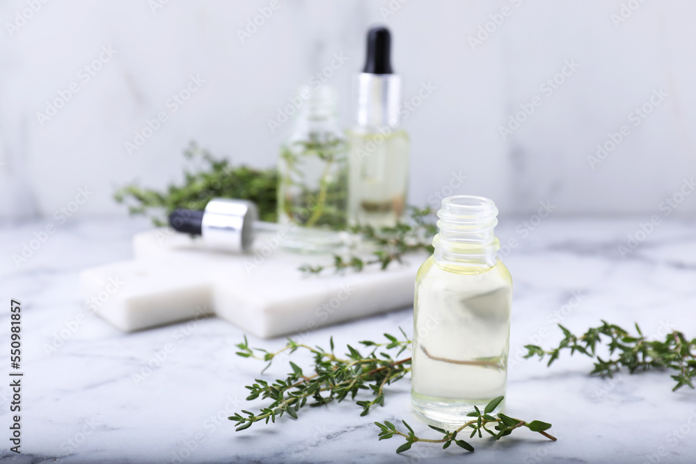 Thyme essential oil on white marble table, space for text Thyme essential oil on white marble table, space for text