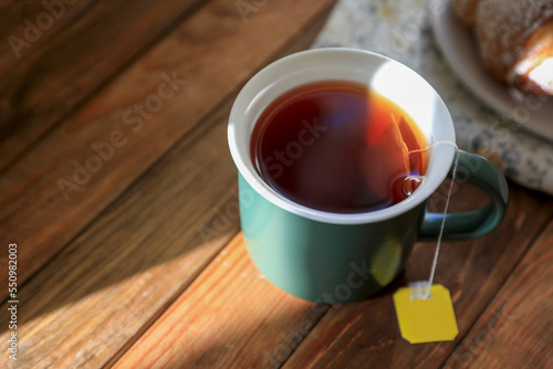 Tea bag in cup on wooden table, closeup. Space for text
