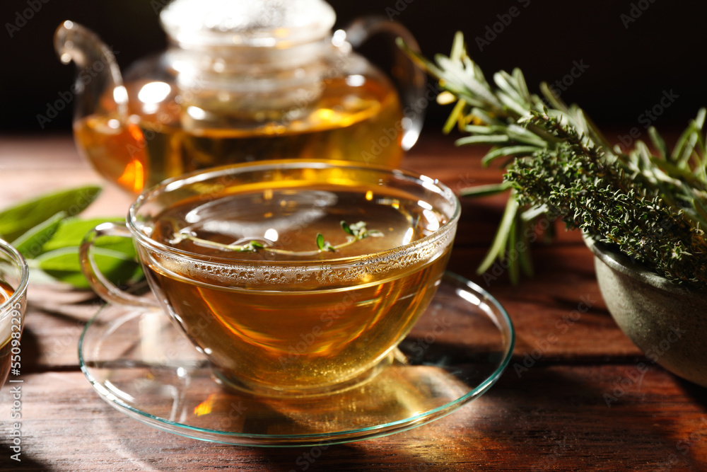 Cup of aromatic herbal tea, fresh rosemary and thyme on wooden table Cup of aromatic herbal tea, fresh rosemary and thyme on wooden table