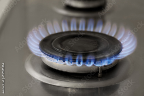 Gas burner with burning flame on cooktop, closeup