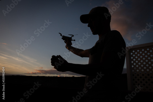 Silhouette of a drone pilot about to fly his drone during sunset.