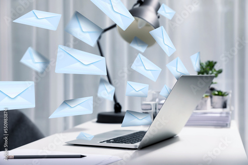 Valokuva Email spam. Workplace with laptop and many letters