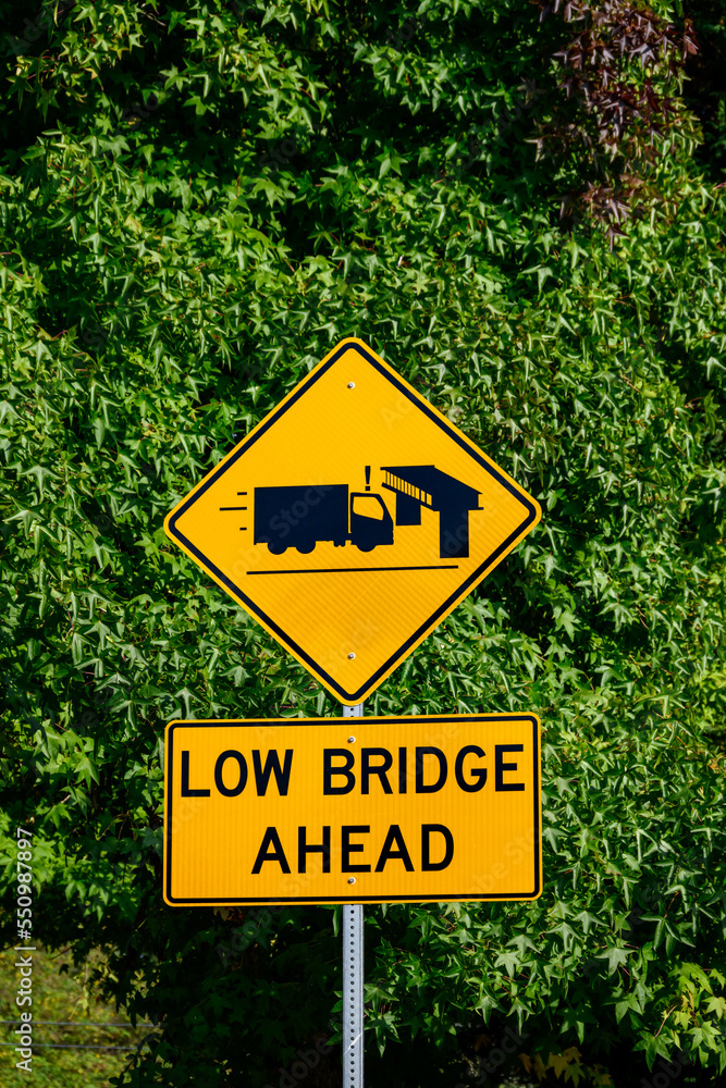 Yellow road sign, Low Bridge Ahead with a truck and bridge symbol, caution to tall vehicles
