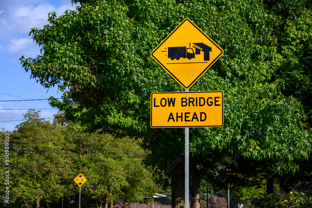 Yellow road sign, Low Bridge Ahead with a truck and bridge symbol, caution to tall vehicles
