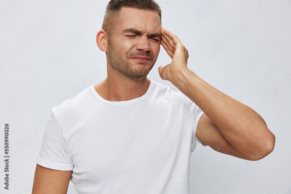 Man headache, migraine, high fever, in white T-shirt on white isolated background, copy space Man headache, migraine, high fever, in white T-shirt on white isolated background, copy space