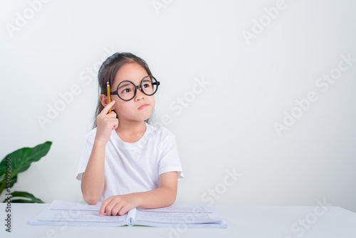 Portrait of little pupil writing at desk in Student girl study doing test in primary school. Children writing notes in classroom. Education knowledge concept