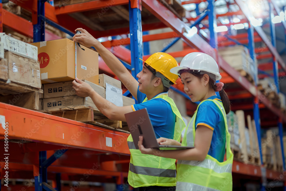Asian engineer in helmets order and checking goods and supplies on shelves with goods background in warehouse.logistic and business export ,Warehouse worker checking packages on shelf in a large store Asian engineer in helmets order and checking goods and supplies on shelves with goods background in warehouse.logistic and business export ,Warehouse worker checking packages on shelf in a large store
