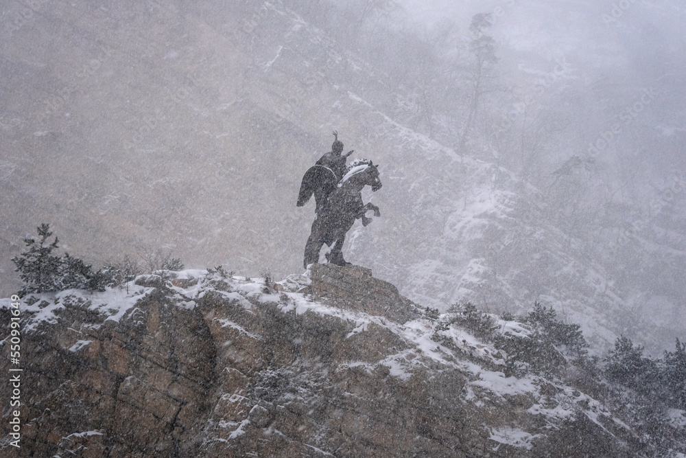 Obraz premium View of Uastyrdzhi monument in Urukh river canyon at winter snowfall. Mountain Digoria, North Ossetia, Russia.